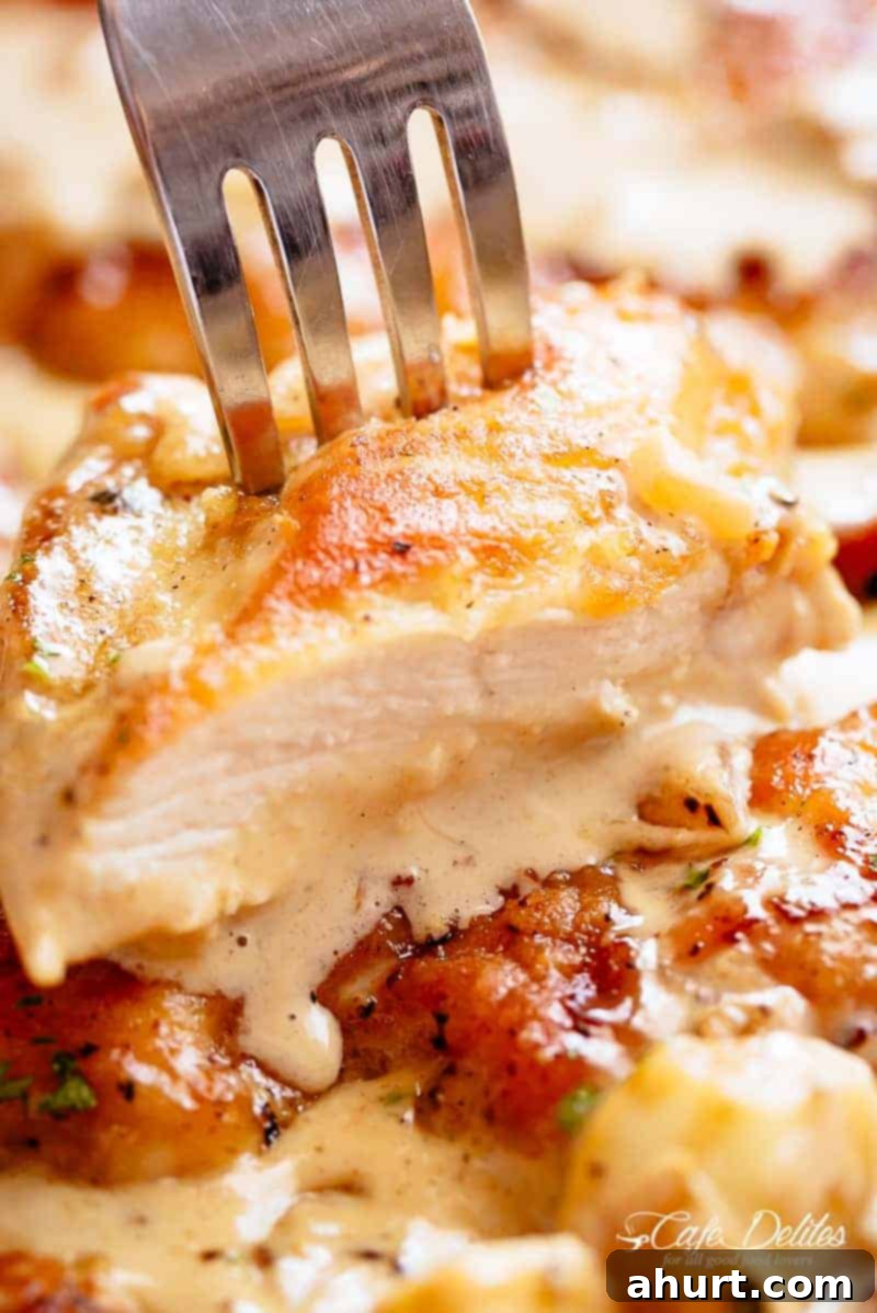 Irresistible Creamy Garlic Chicken Breasts 3 A silver fork expertly pierces through a perfectly sliced piece of tender, creamy garlic chicken, ready to be enjoyed.