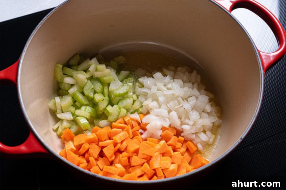 Rich Ham and Potato Chowder 3 Image of carrots, onions, and celery being sautéed in a pan.