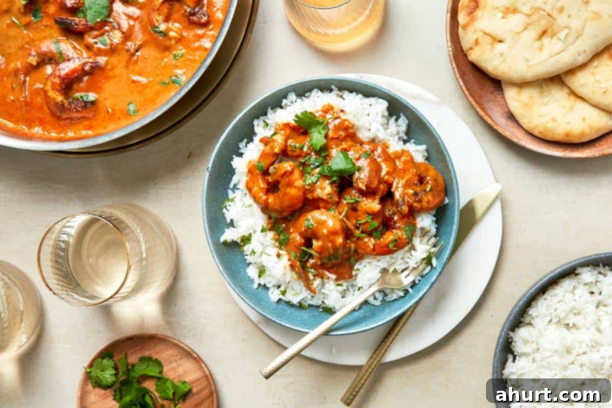 Easy Creamy Coconut Shrimp Curry 11 A dining table displaying vibrant bowls of curry alongside bowls of fluffy rice, ready to be served with warm naan.