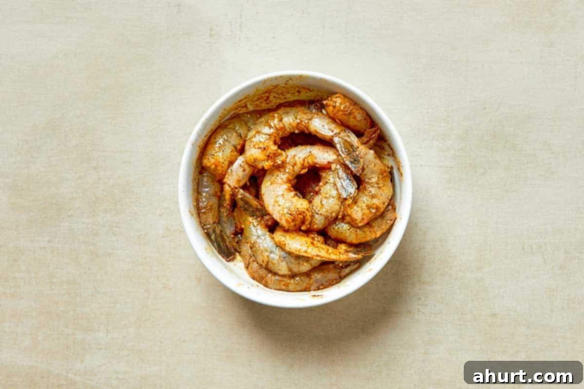 Easy Creamy Coconut Shrimp Curry 4 A bowl of shrimp served in a white dish, placed on a wooden table.