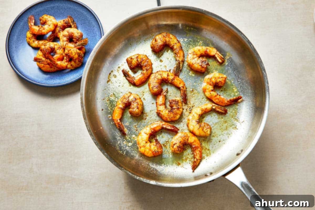 Easy Creamy Coconut Shrimp Curry 5 A frying pan with shrimp beside a colorful plate of food, showcasing a delicious meal.