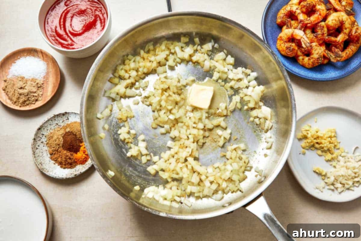 Easy Creamy Coconut Shrimp Curry 6 A pan with chopped onion and other ingredients arranged on a wooden table.