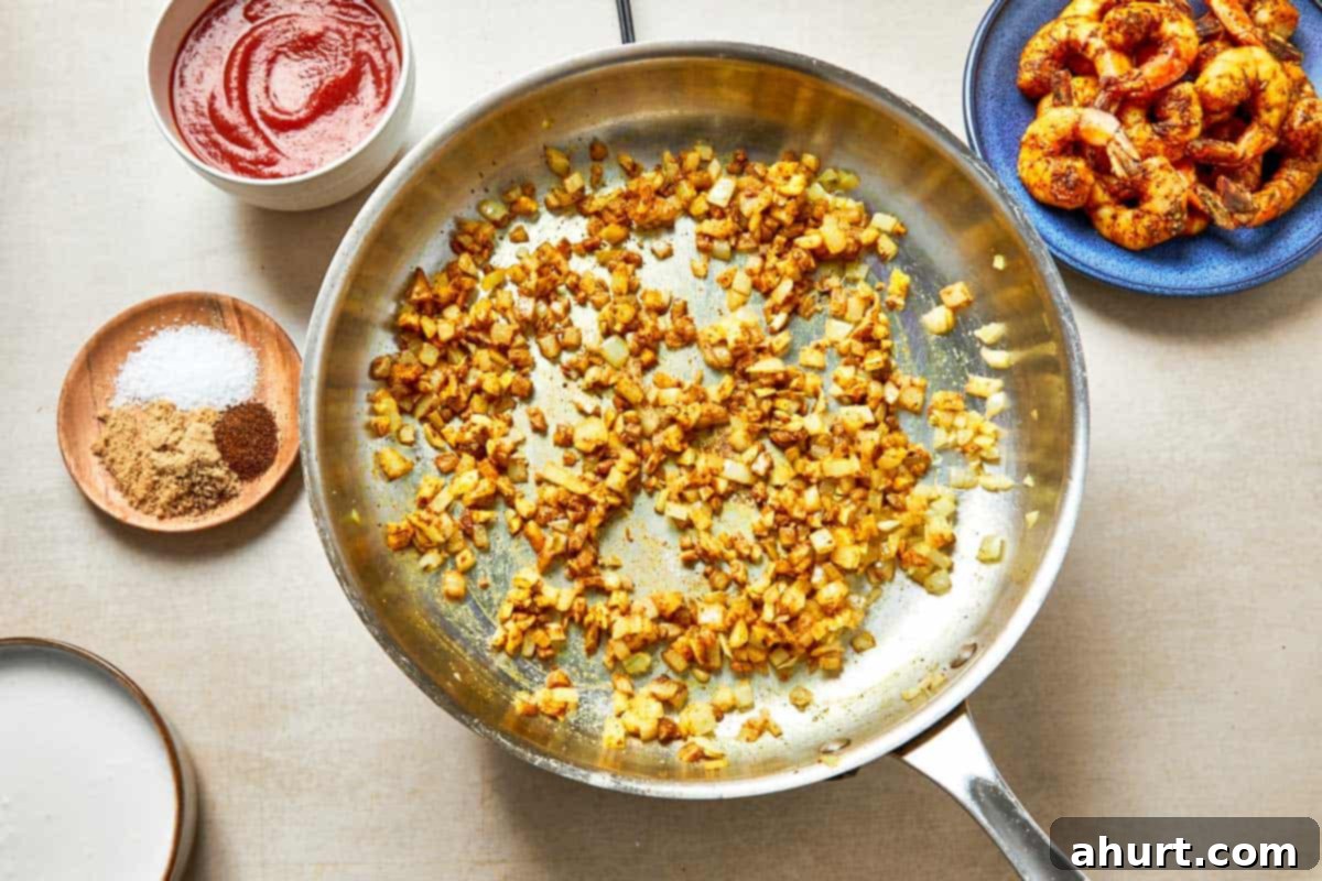 Easy Creamy Coconut Shrimp Curry 7 A skillet filled with golden onion, and other colorful ingredient