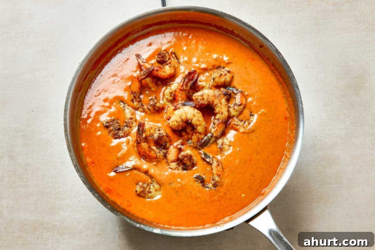 Easy Creamy Coconut Shrimp Curry 9 A pan filled with pink, plump shrimp simmering in a rich sauce.