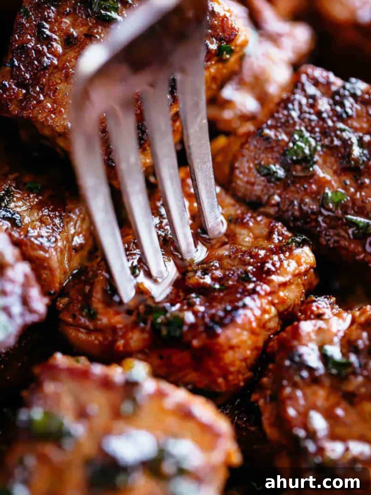 Irresistible Cajun Butter Steak Bites 10 A silver fork pierces a steak bite with crispy edges