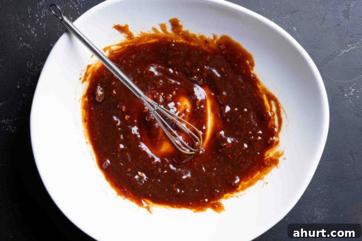 Spicy Firecracker Salmon 3 An image of the ingredients for the firecracker sauce being whisked together in a bowl until smooth and well combined.
