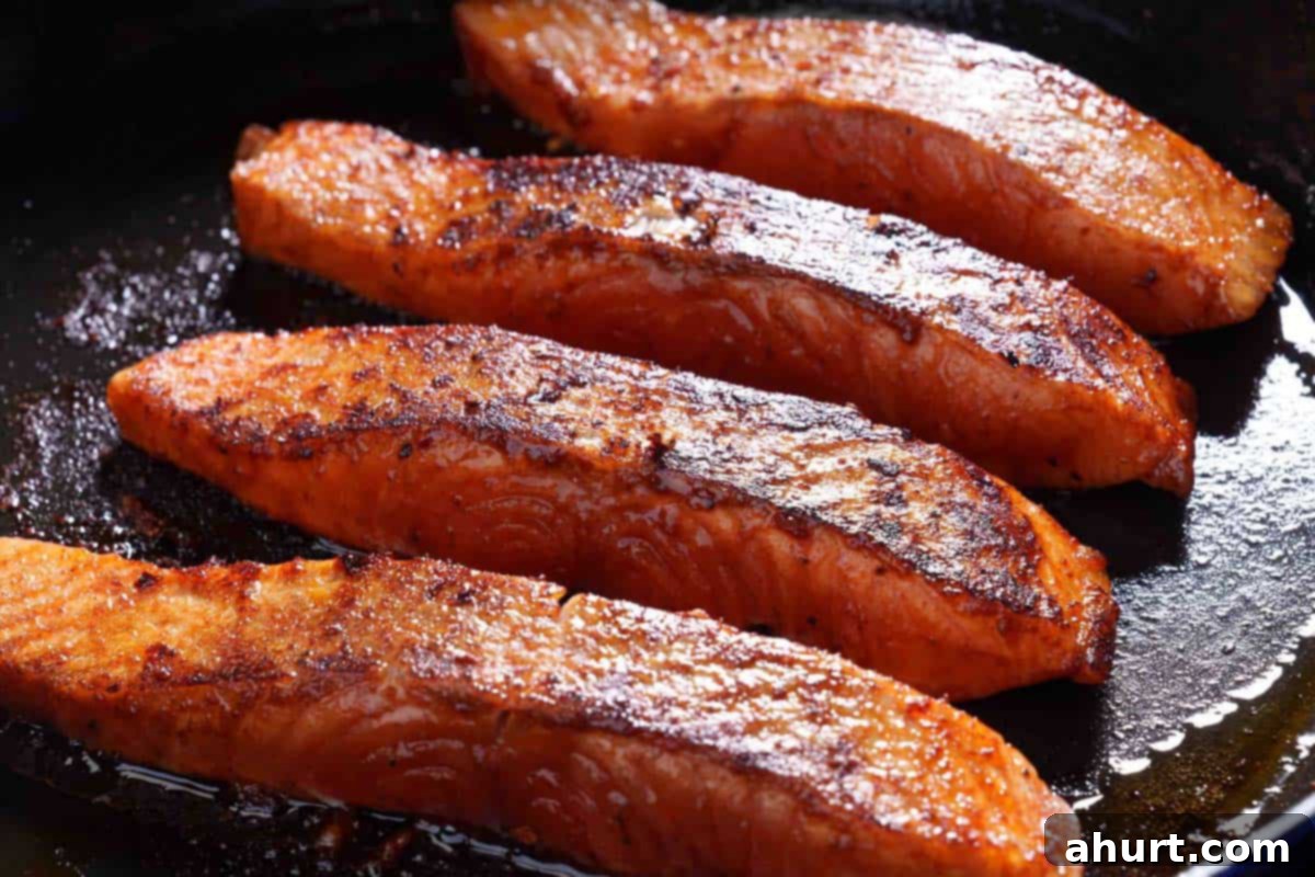 Spicy Firecracker Salmon 7 Image of the salmon being seared to perfection in a hot skillet, cooking on both sides to achieve a beautiful, crispy crust.