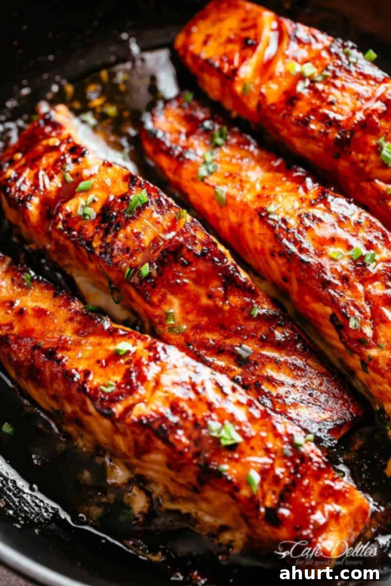 Spicy Firecracker Salmon 9 Close-up image of perfectly crispy firecracker salmon fillets coated in vibrant, glossy sauce, garnished with fresh herbs.
