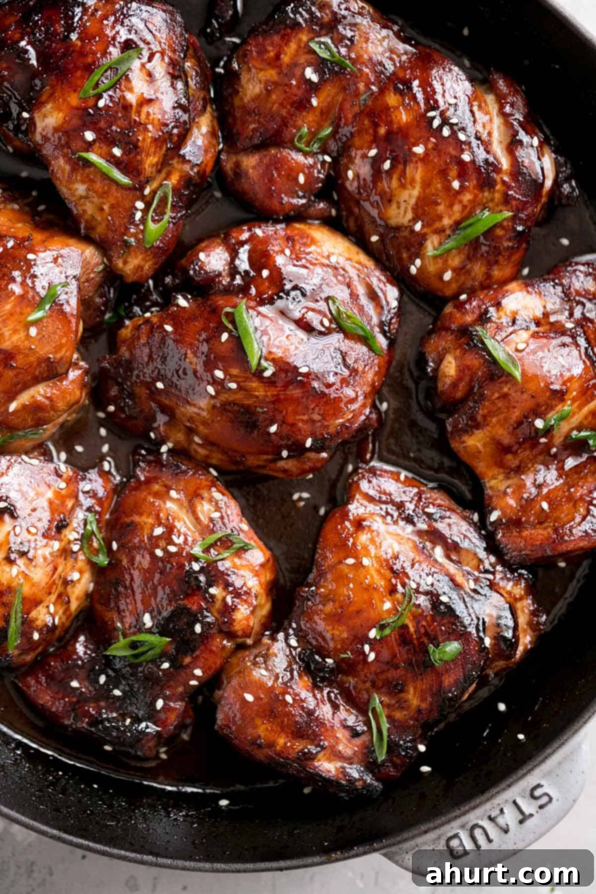 Honey Soy Glazed Chicken Thighs 2 Close-up top view of honey soy baked chicken thighs in a black skillet, roasted in the oven and glazed in a dark sauce.