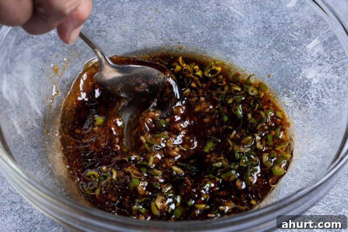 Honey Soy Glazed Chicken Thighs 4 Honey, soy sauce, green onions, cooking oil, garlic, vinegar, sesame oil, and ginger are being mixed together in a clear bowl.
