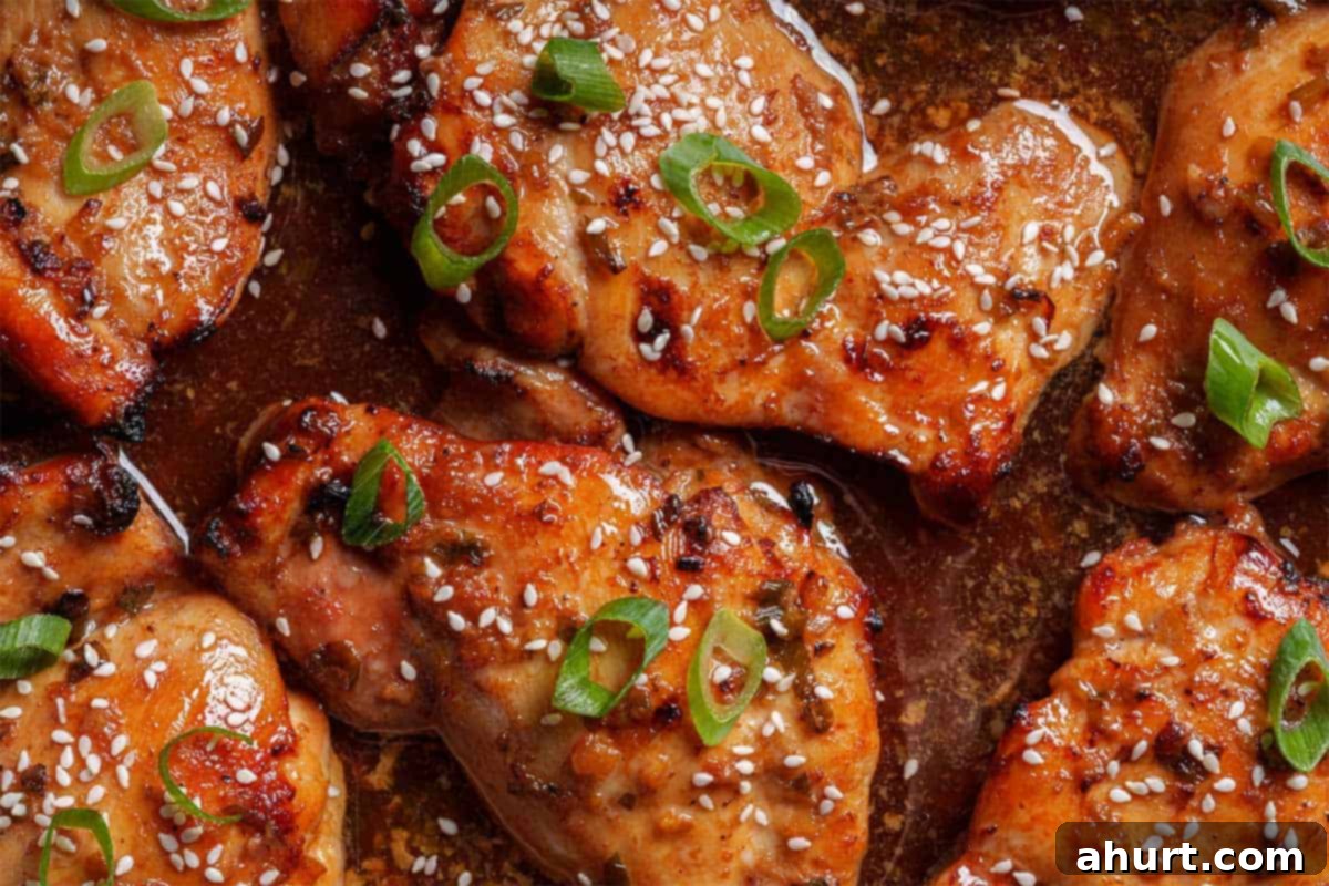 Honey Soy Glazed Chicken Thighs 8 Close-up image of the chicken being taken out of the oven, garnished with sesame seeds and chives.