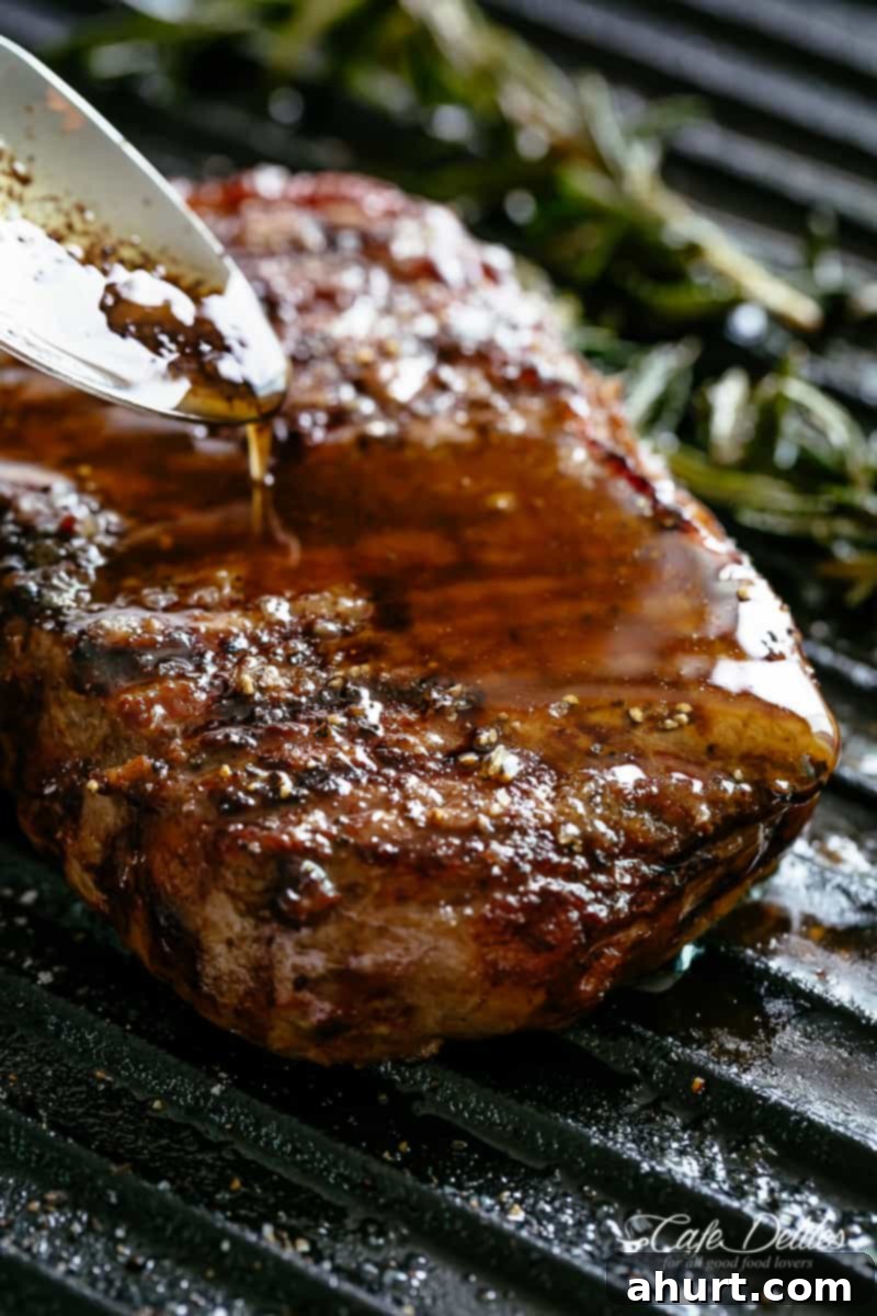 Zoomed-in image of a juicy Grilled Steak, beautifully seared and glistening, drizzled generously with garlic and pepper Browned Butter.