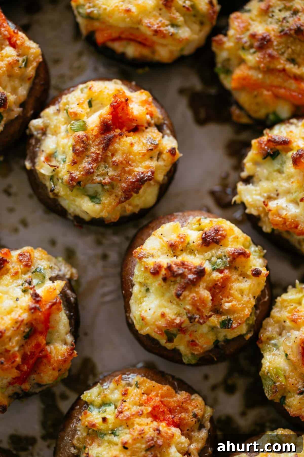 Perfectly baked Crab Stuffed Mushrooms, golden and inviting. Three golden brown crab stuffed mushrooms on a baking tray, ready to be served.