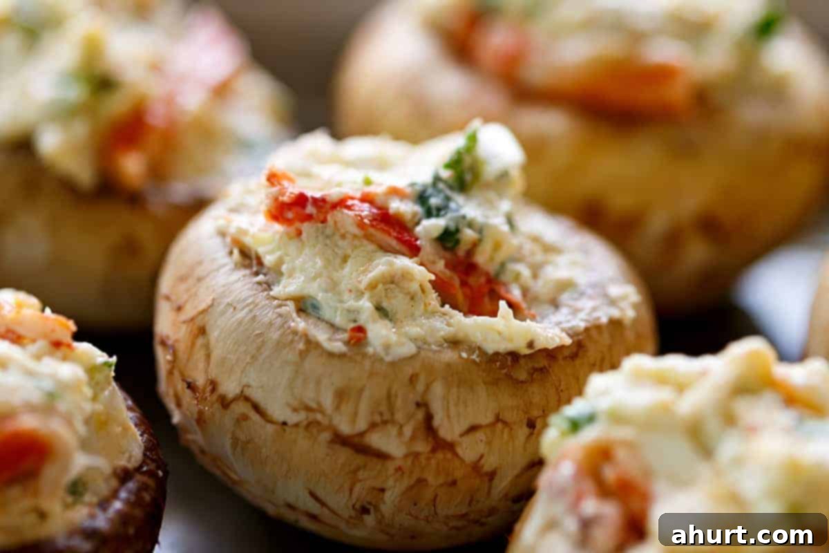 Raw crab dip stuffed mushrooms, perfectly prepped before baking. Close-up of mushroom caps generously stuffed with uncooked crab dip, ready for the oven.