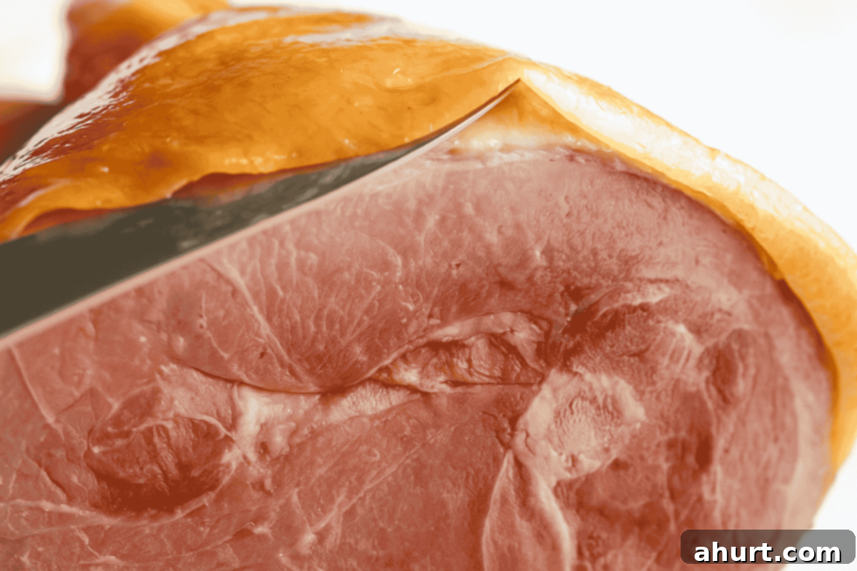 Caramelized Maple Ham 5 A sharp knife carefully separating the ham rind from the underlying fat layer, ensuring the fat remains intact.