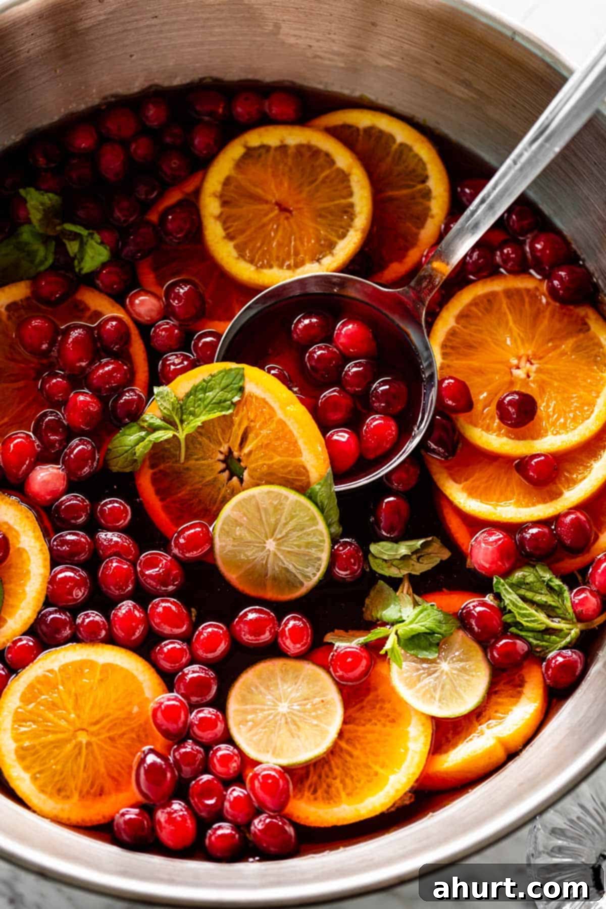 Festive Holiday Punch 2 Vibrant Mixed Fruit Holiday Punch in a large glass bowl, garnished with fresh fruit and mint