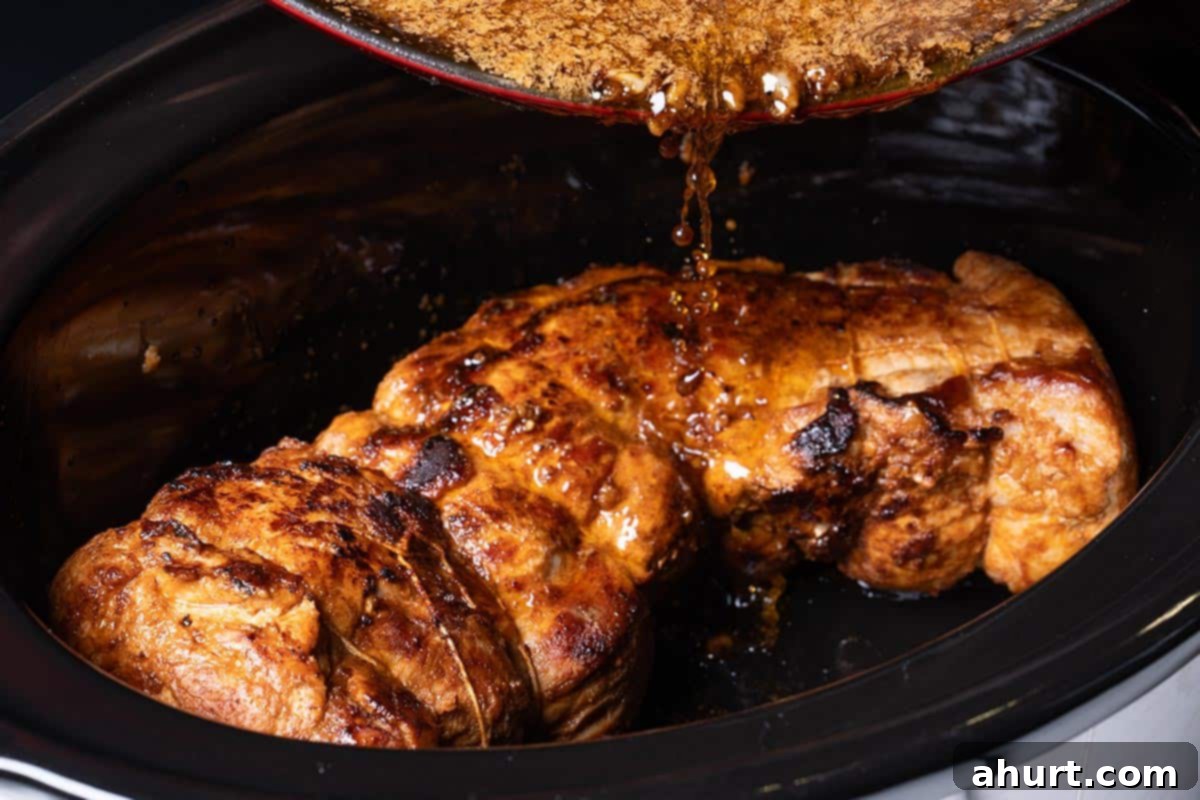 Tender & Juicy Oven-Roasted Pork Loin 6 Seared pork loin being placed into a slow cooker and covered with the sauce.