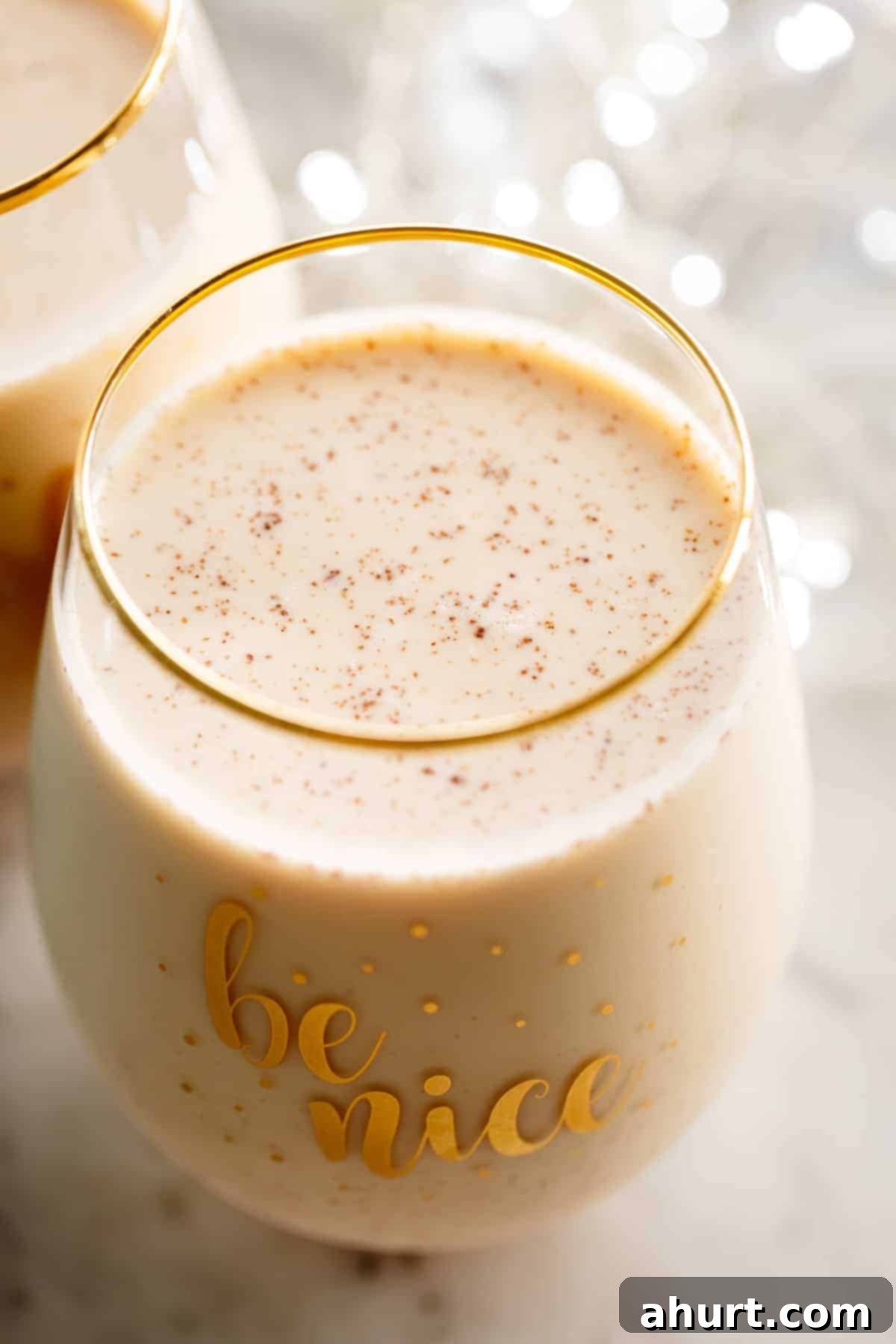 easy eggnog recipe, best homemade eggnog, creamy christmas drink, holiday eggnog Eggnog resting in a fancy glass, garnished with cinnamon