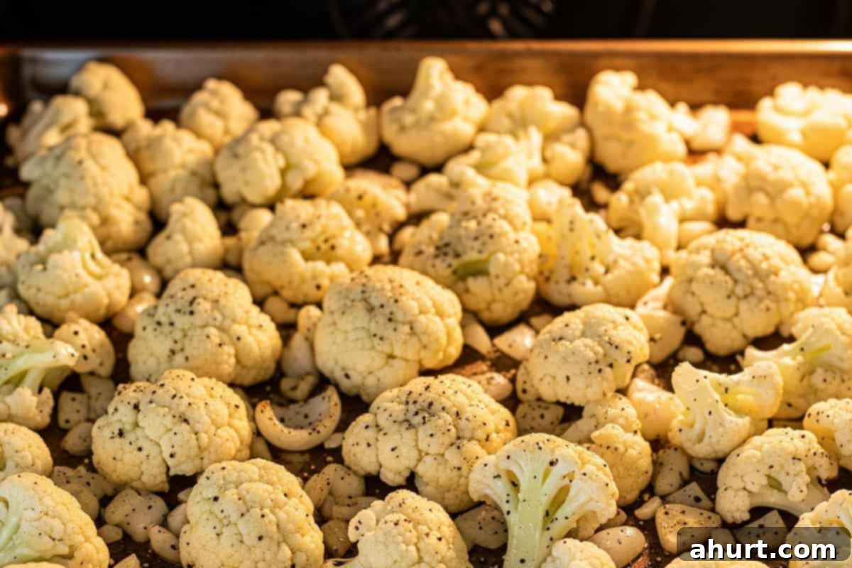 Roasted Cauliflower 6 Cauliflower, onion, and garlic spread in a single layer on a baking sheet inside the oven.