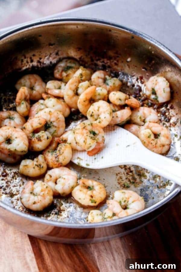 A spoon stirring Lemon Paprika Garlic Prawns in a pan 