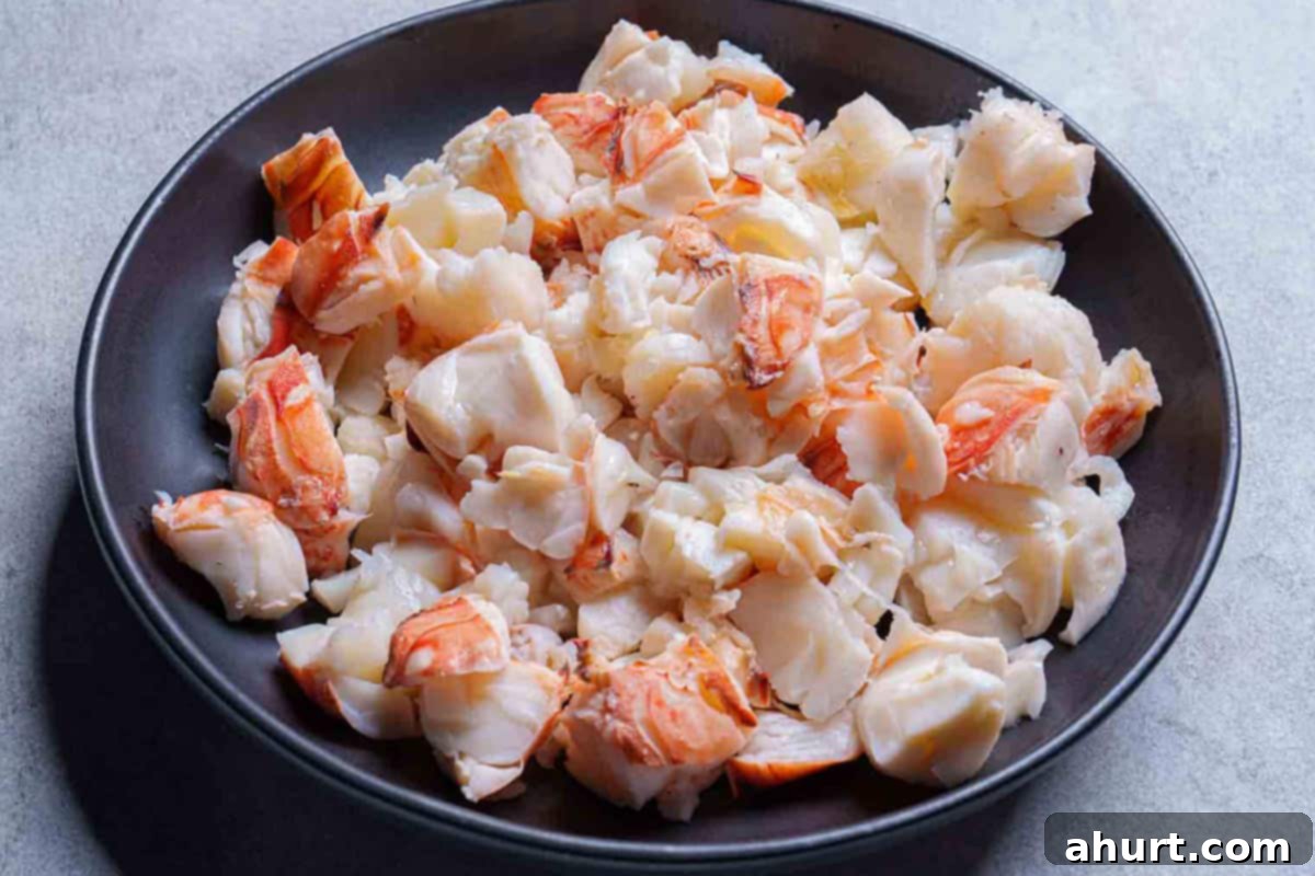 Luxurious Lobster Bisque 7 Carefully chopped lobster meat, portioned into bite-sized chunks, resting in a black bowl, ready for chilling.