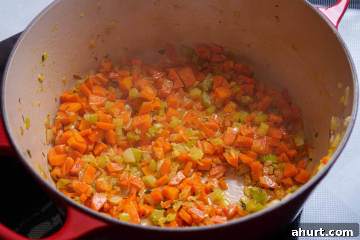 Luxurious Lobster Bisque 8 Finely chopped onions, carrots, and celery being sautéed in a pan with butter and olive oil until they are tender and translucent.