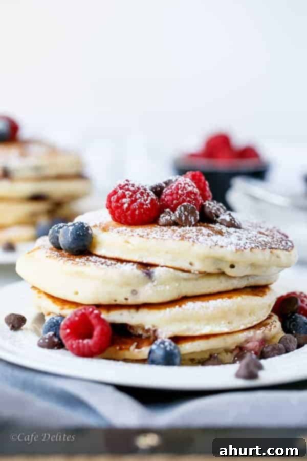 Greek Yogurt Berry Chocolate Chip Cloud Cakes 2 A stack of golden brown, fluffy Greek Yogurt and Mixed Berry Chocolate Chip Pancakes with fresh berries on top, ready to be drizzled.
