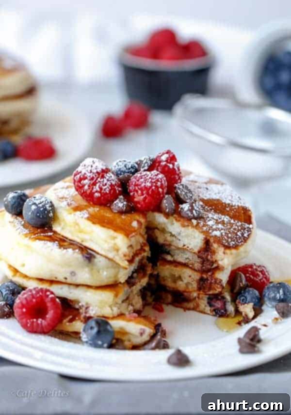 Greek Yogurt Berry Chocolate Chip Cloud Cakes 4 A slice of Fluffy Greek Yogurt and Mixed Berry Chocolate Chip Pancake being lifted, revealing the moist interior, berries, and melted chocolate.