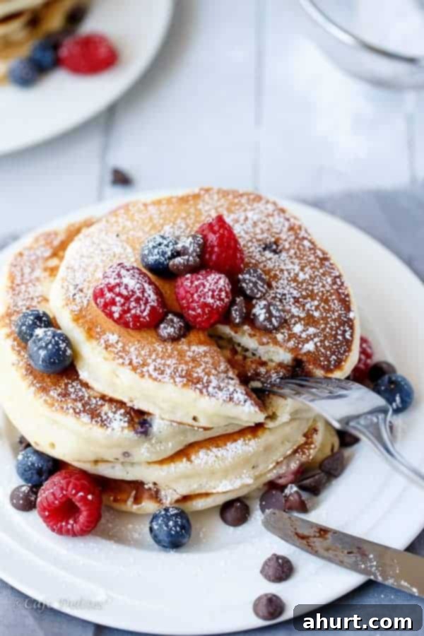 Greek Yogurt Berry Chocolate Chip Cloud Cakes 5 An overhead view of Fluffy Greek Yogurt Mixed Berry Chocolate Chip Pancakes, showcasing the golden color and berry distribution.