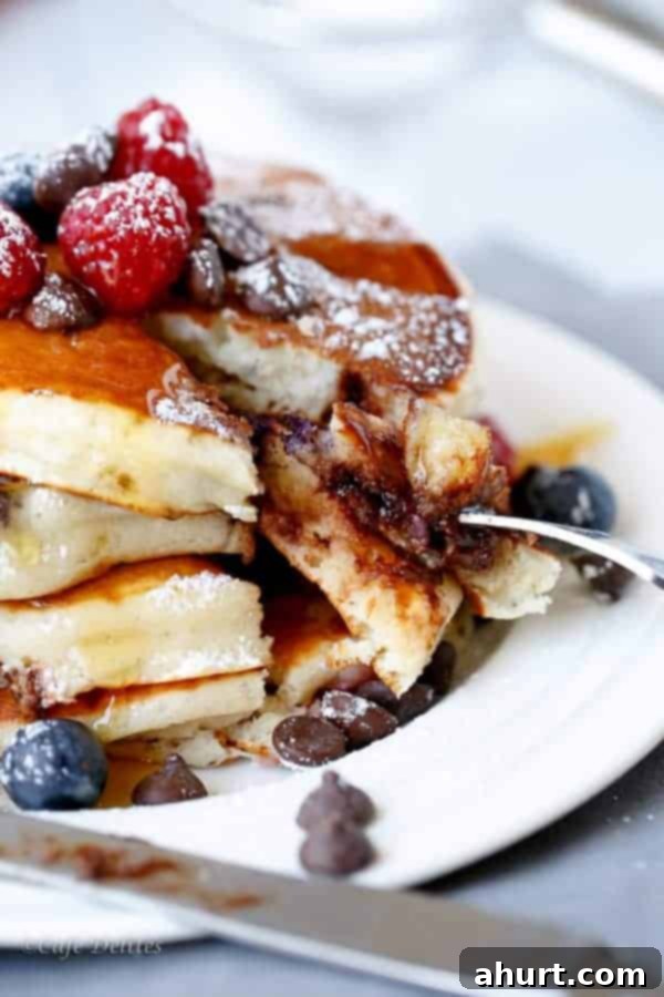 Greek Yogurt Berry Chocolate Chip Cloud Cakes 6 Side view of Fluffy Greek Yogurt Mixed Berry Chocolate Chip Pancakes, showing the layers and thickness, with a generous topping of fresh berries.