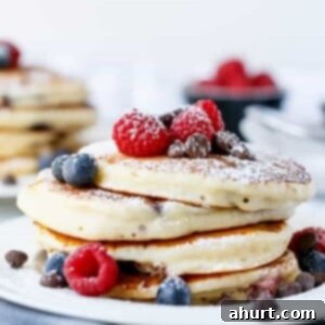 Greek Yogurt Berry Chocolate Chip Cloud Cakes 7 Fluffy Greek Yoghurt and Mixed Berry Choc Chip Pancakes being stack on each other with some fresh berries on top