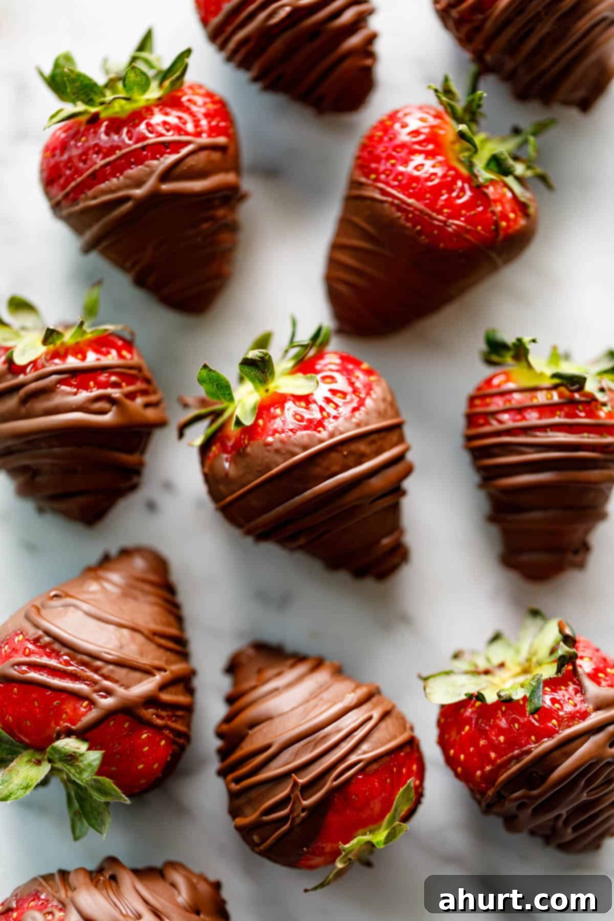 chocolate covered strawberries #valentinesday #chocolatecoveredstrawberry Top view looking at a finished batch of drizzled strawberries coated with chocolate on a marble bench.