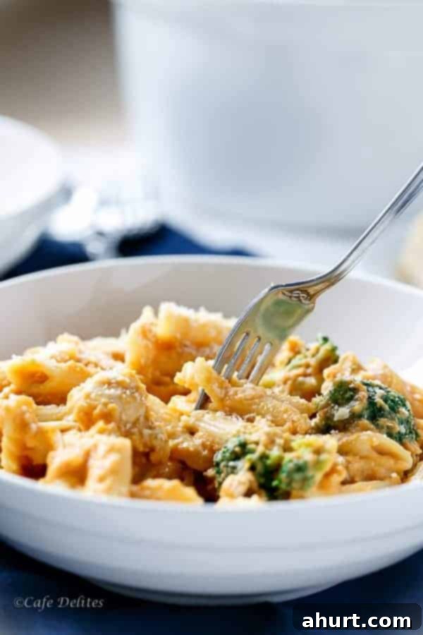 Velvety Pumpkin Chicken Alfredo with Broccoli 4 A fork pierced into a piece from Creamy Pumpkin Chicken and Broccoli Alfredo, lifting pasta and chicken