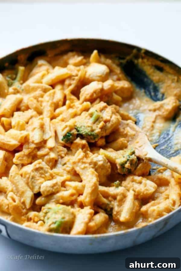 Velvety Pumpkin Chicken Alfredo with Broccoli 5 Creamy Pumpkin Chicken and Broccoli Alfredo being cooked in a pan, stirring the sauce