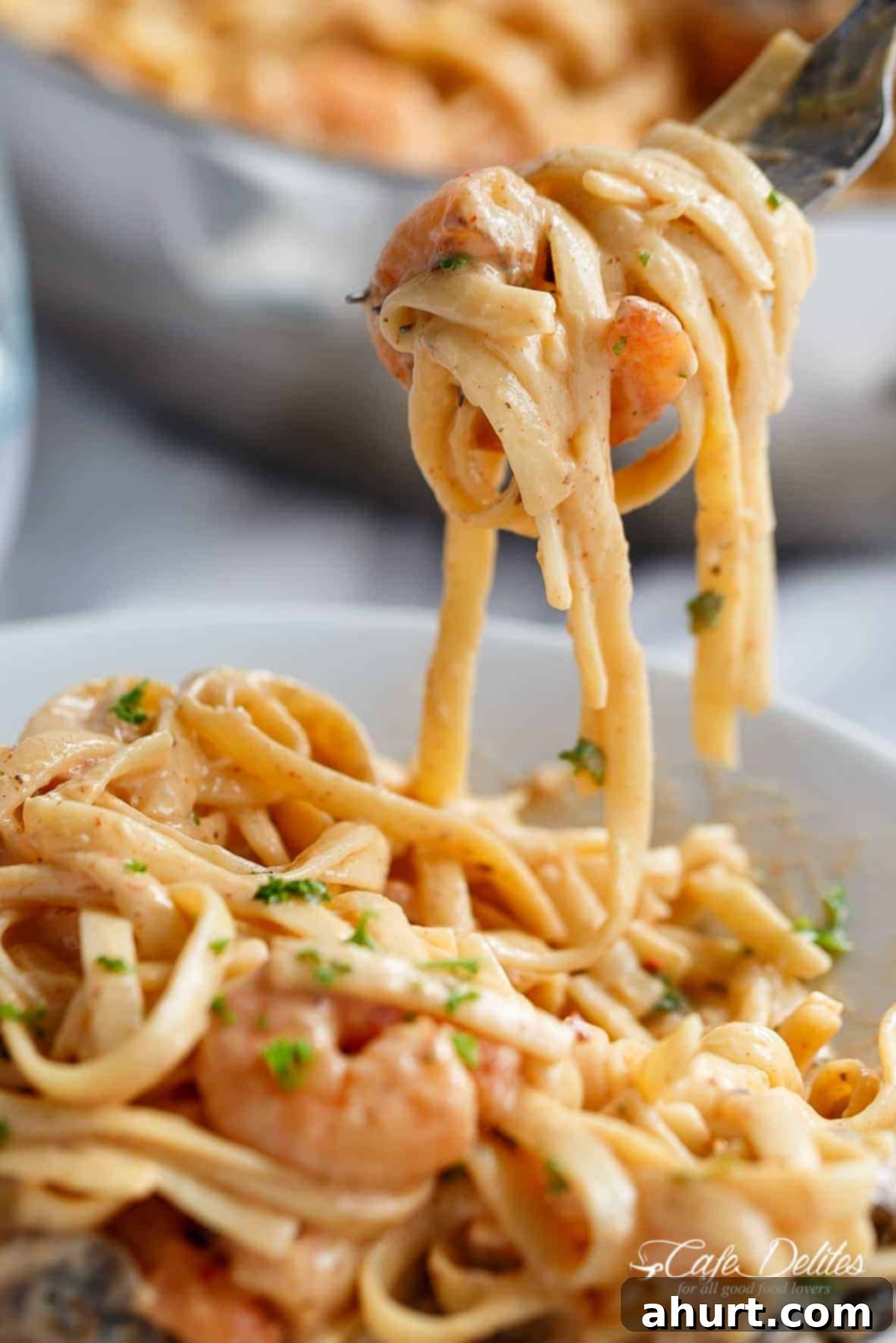 Delicious Creamy Shrimp Pasta Video 3 Close-up of a fork lifting Creamy Shrimp Pasta, showing succulent shrimp and pasta coated in garlic parmesan Alfredo sauce.