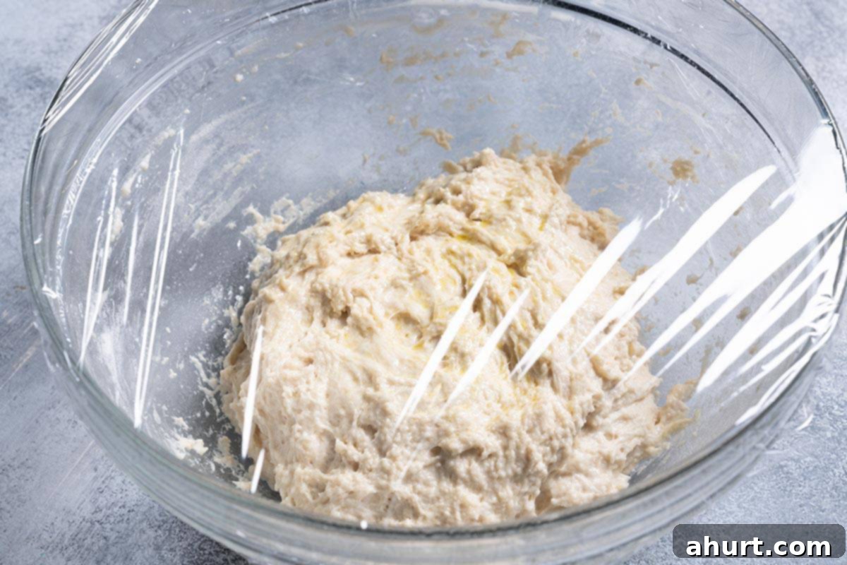 Effortless Artisan Crust: No-Knead Perfection 5 The bowl containing all the ingredients is lightly sprayed with cooking oil and covered with cling wrap.