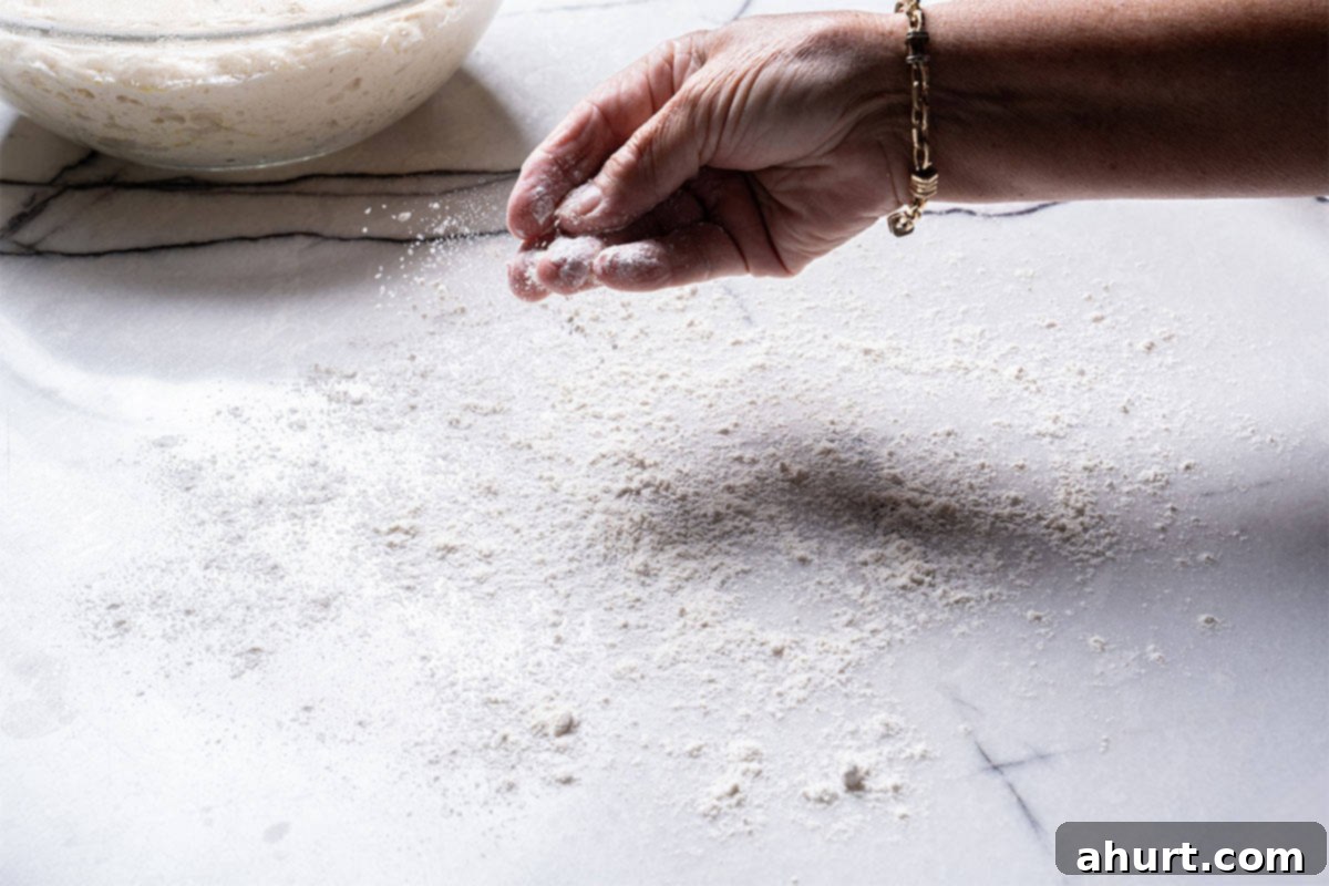Effortless Artisan Crust: No-Knead Perfection 8 A surface being lightly floured by a hand.