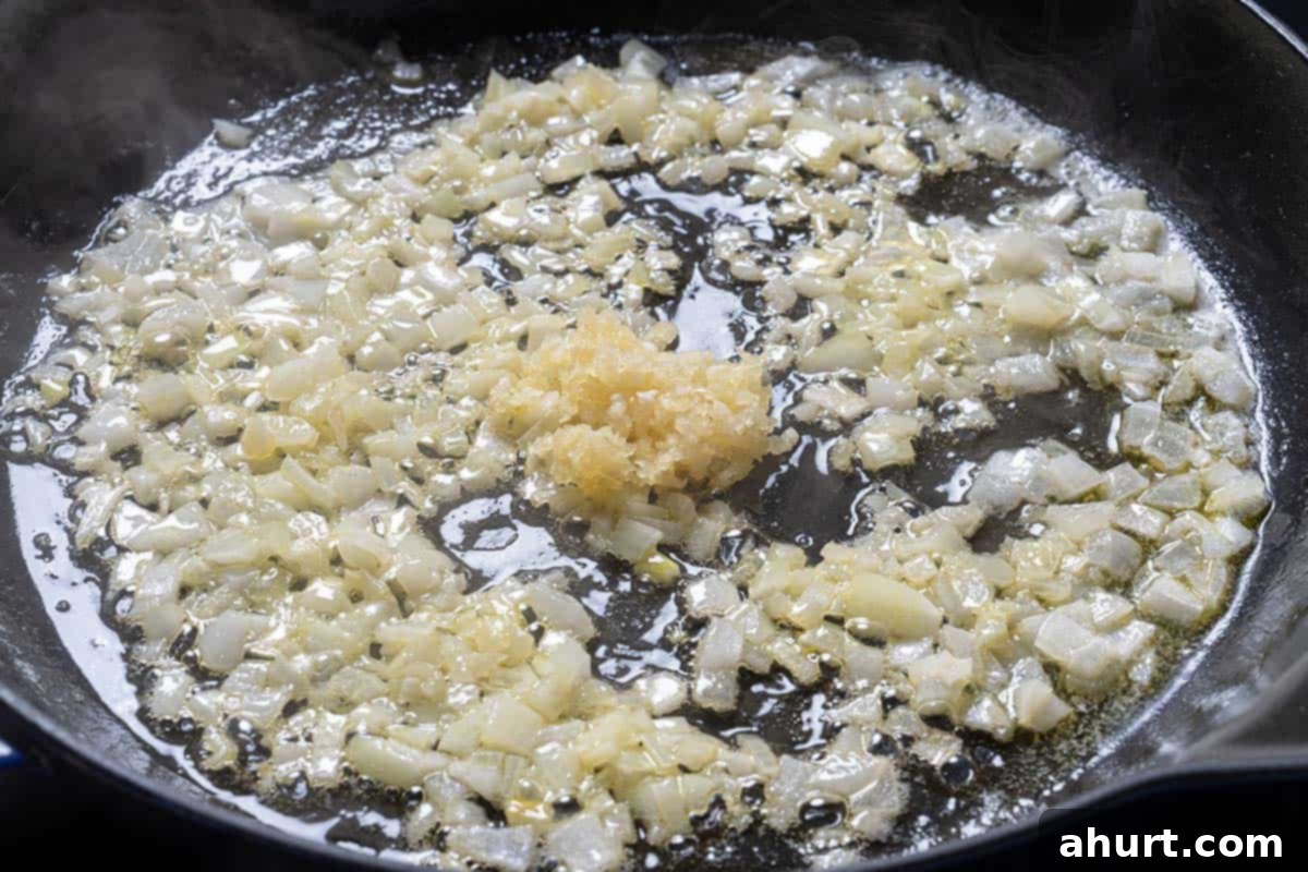 Dreamy Creamy Tuscan Gnocchi 4 Image of shallots and garlic cooking in a pan.