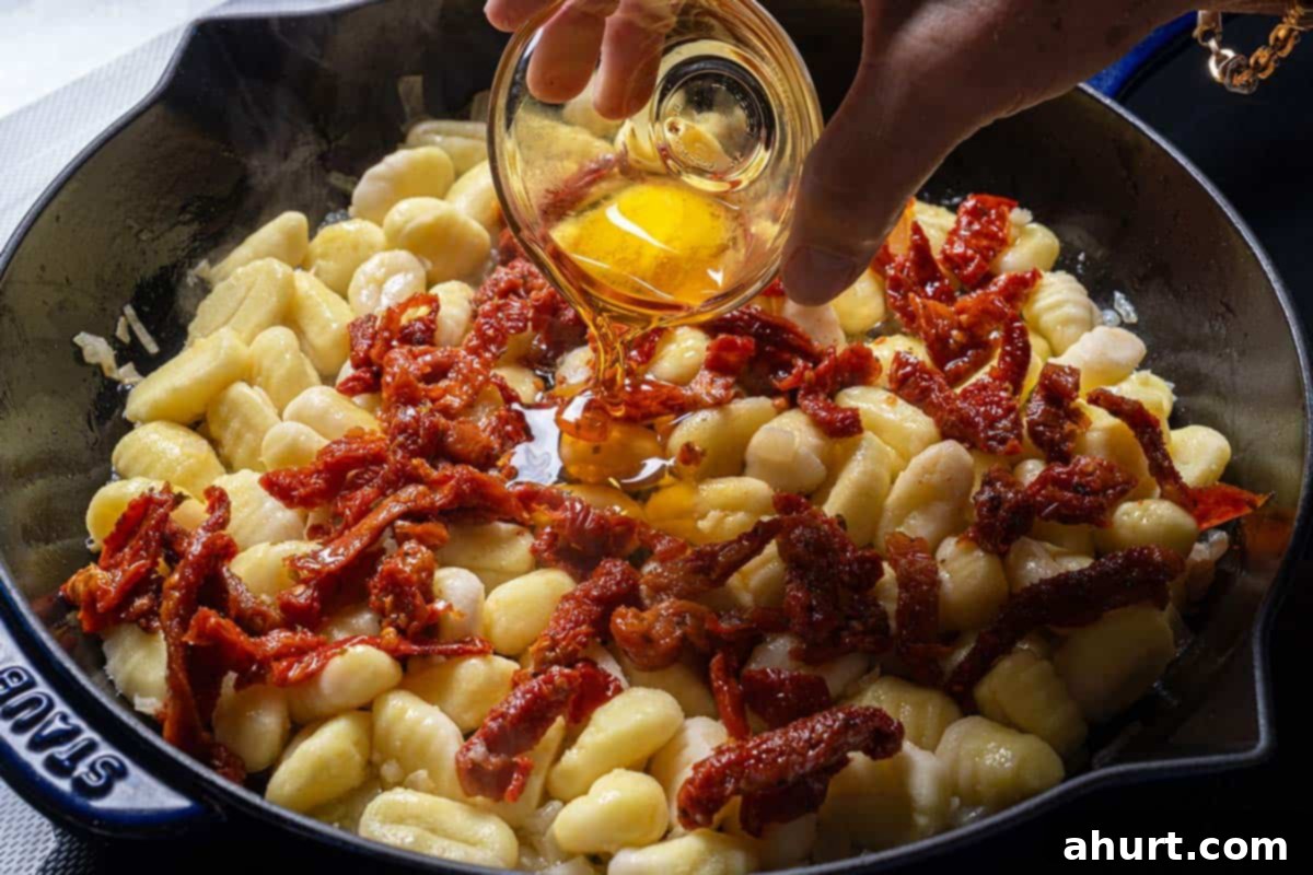 Dreamy Creamy Tuscan Gnocchi 5 Image of gnocchi and sun-dried tomatoes searing in a pan.