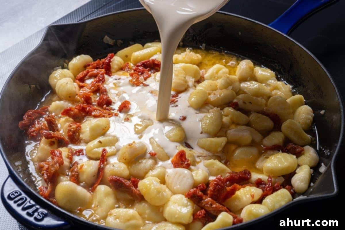 Dreamy Creamy Tuscan Gnocchi 6 Image of broth, cream, and herbs added to the pan.