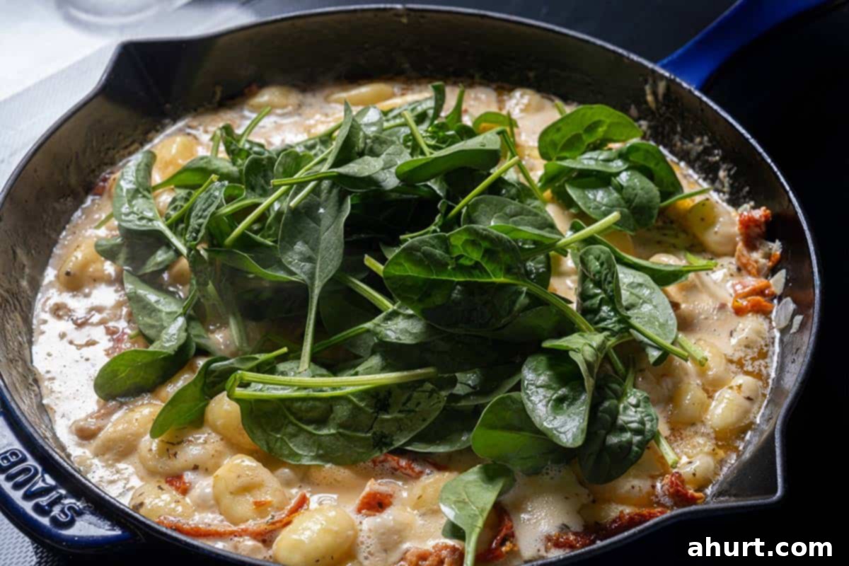 Dreamy Creamy Tuscan Gnocchi 8 Image of spinach wilting in the gnocchi sauce.