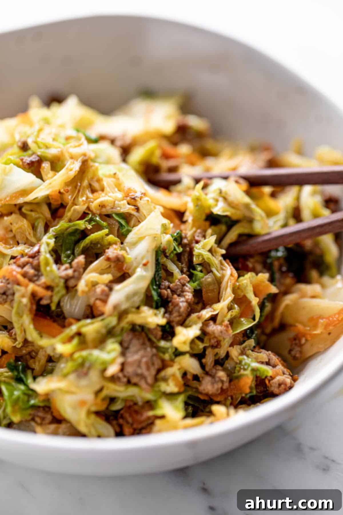 Ground Beef in a white bowl with cabbage, served with chop sticks. A delicious and healthy meal option.