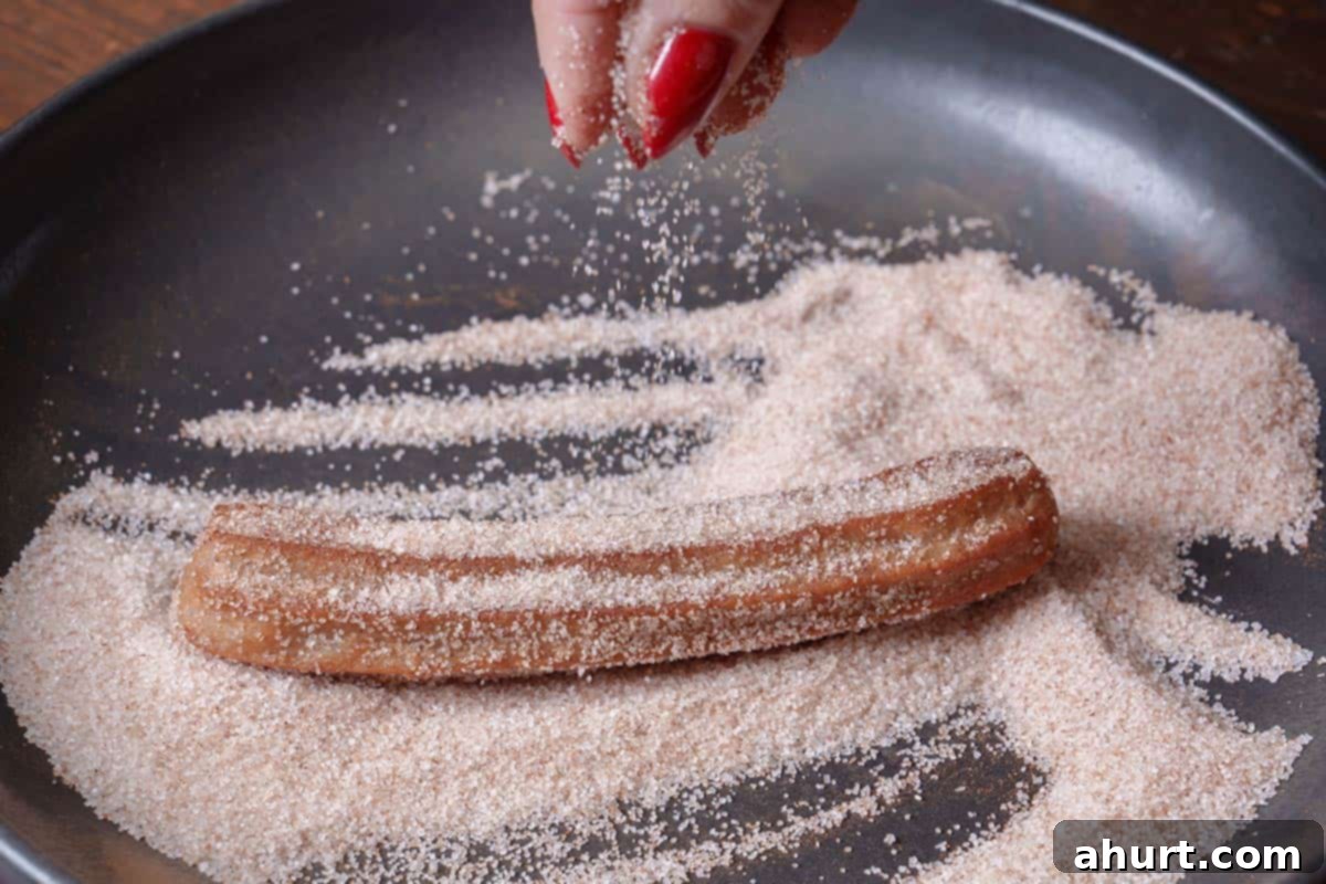 The Ultimate Churros Recipe 9 A churro is being removed from the frying pan and dipped into sugar and cinnamon.
