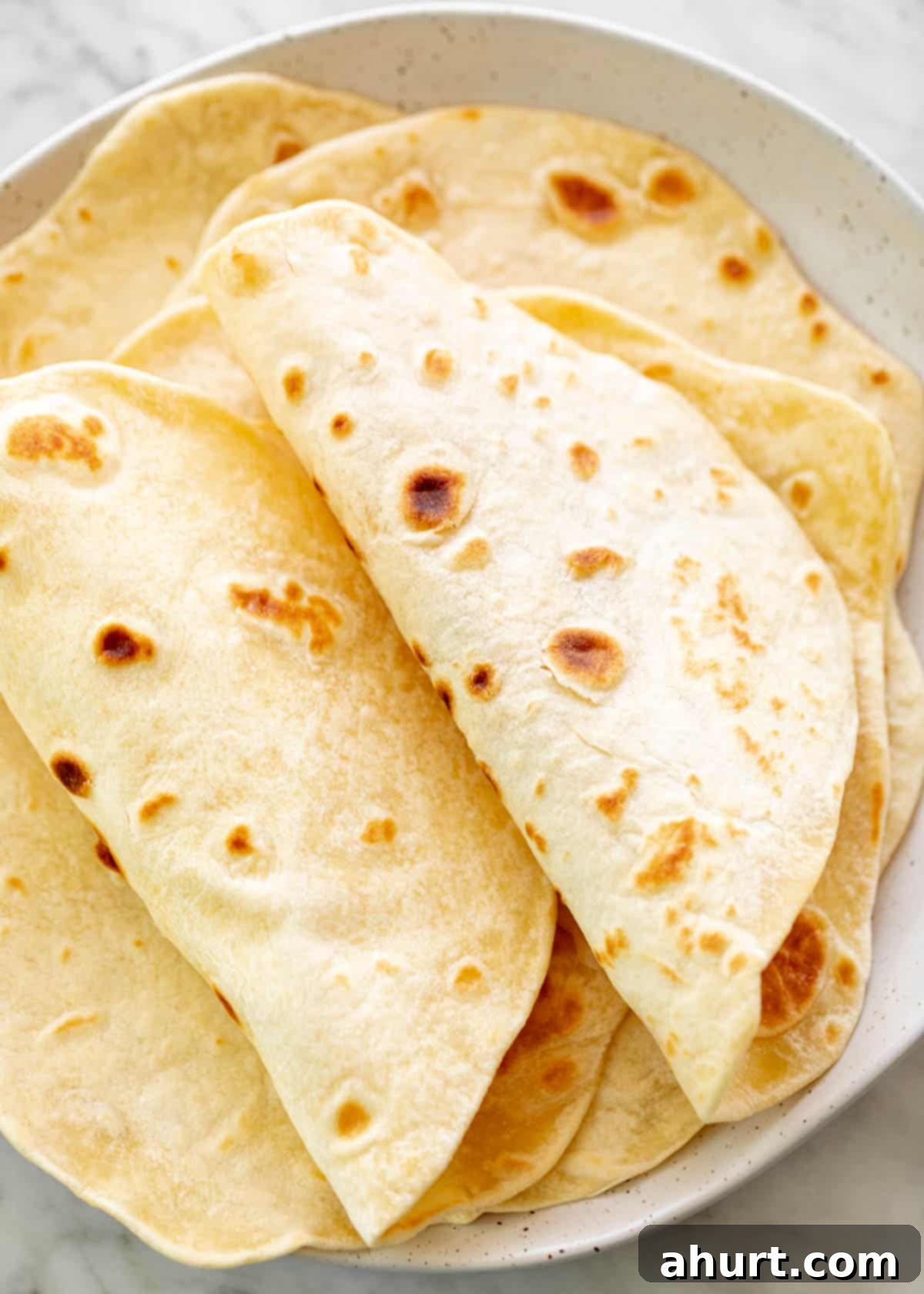 Perfect Homemade Flour Tortillas 10 Freshly prepared Folded flour tortillas on a plate.