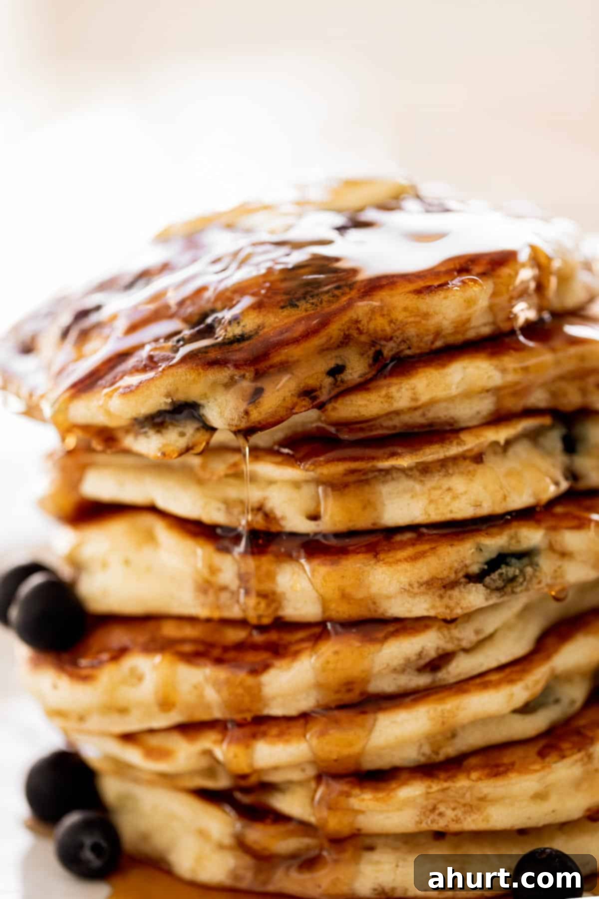 Morning Blueberry Bliss 8 A beautiful stack of golden blueberry pancakes on a plate, generously drizzled with maple syrup and garnished with fresh blueberries.
