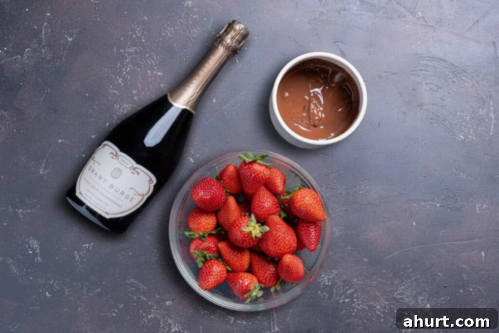 Tipsy Chocolate Strawberries 3 Image showing the essential ingredients for the recipe, including an alcoholic beverage of choice, premium quality chocolate bars, and fresh, vibrant strawberries with their green stems, all neatly laid out.