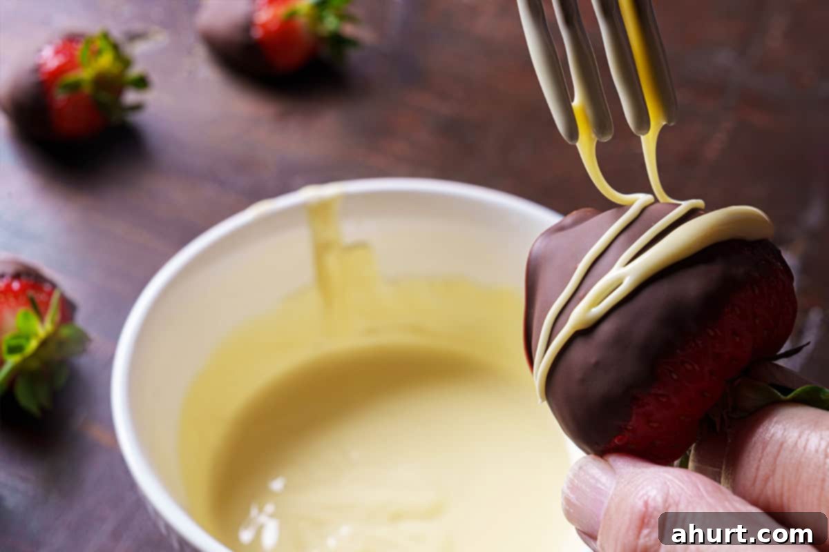 Tipsy Chocolate Strawberries 9 Chocolate-covered strawberries on parchment paper, being artfully drizzled with melted white chocolate in a zig-zag pattern for decoration.