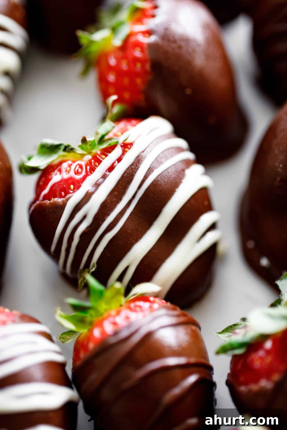 Tipsy Chocolate Strawberries 10 A close-up image of a perfectly coated chocolate-covered strawberry, adorned with an elegant white chocolate drizzle, showcasing its decadent and irresistible texture.