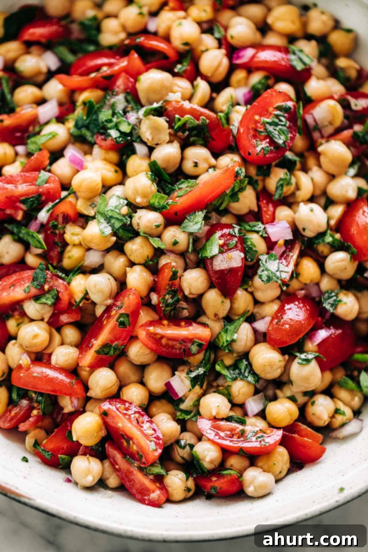 Mediterranean Chickpea Tomato Salad 2 Chickpea Tomato Salad in a white bowl on a white marble table background.