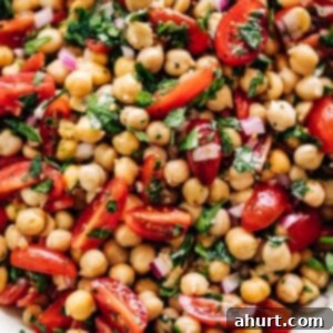 Mediterranean Chickpea Tomato Salad 9 Chickpea Tomato Salad in a white bowl on a white marble table background.